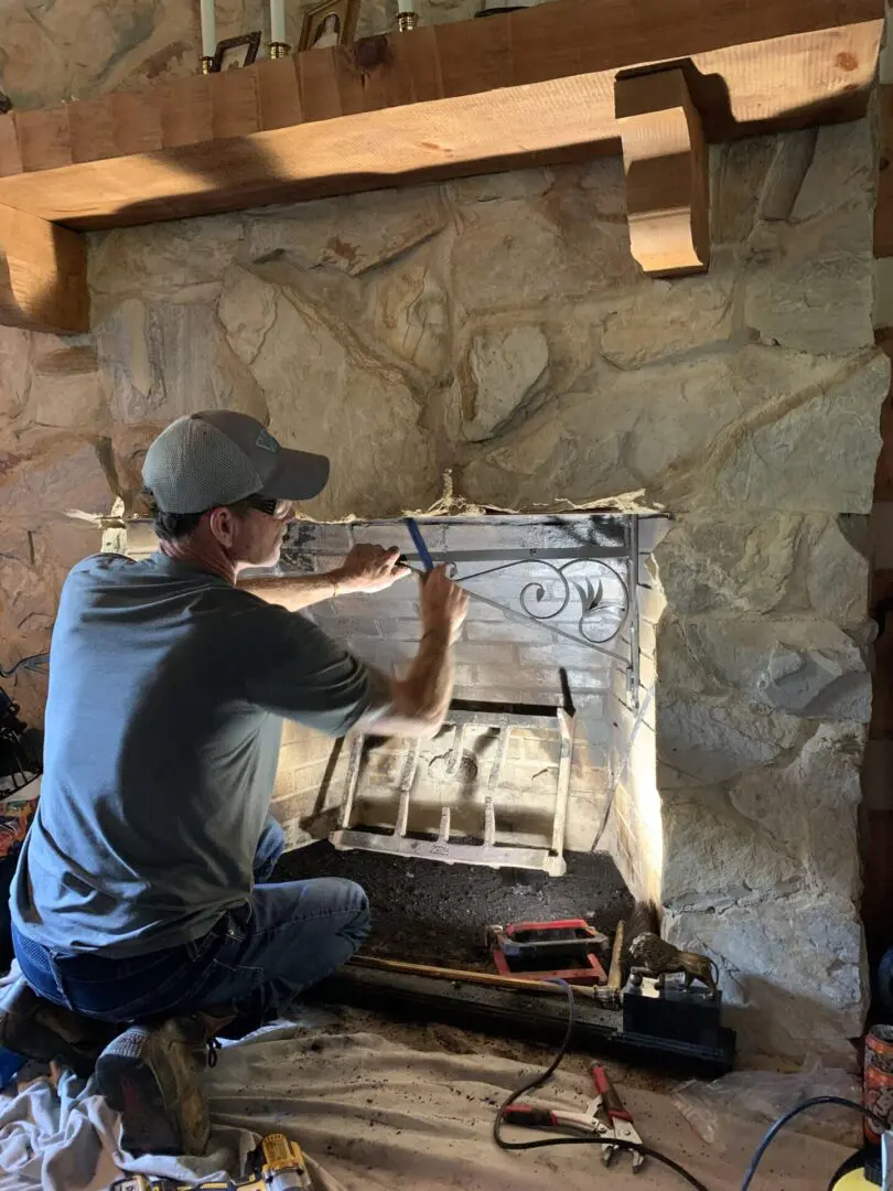 A man is working on an old fireplace.