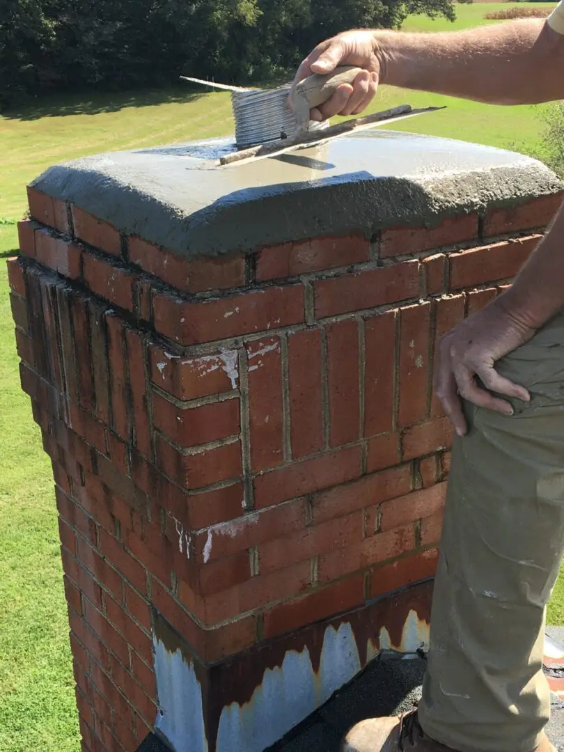 A man standing next to a brick pillar.