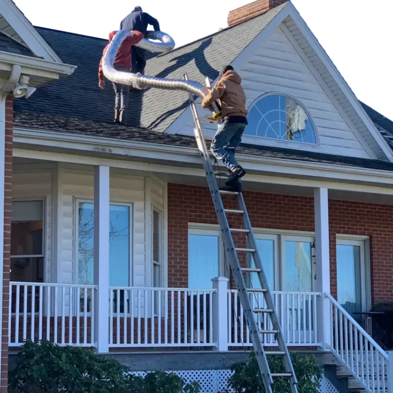 A man on a ladder is climbing up the roof of his house.